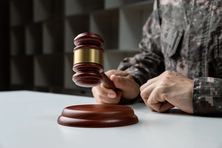 Військовослужбовець у формі тримає суддівський молоток, символізуючи правосуддя у військовому праві